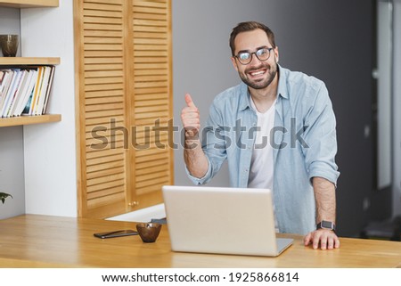Stock photo: A Young Man In Glasses Stands Near A Computer Desk A Young Man Works With A Computer And A Magnetic