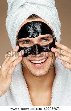 Foto d'archivio: Happy Man With Black Mask On The Face Photo Man Receiving Spa Treatments Beauty Skin Care Concept