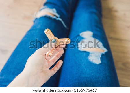 Stock photo: Girl Teenager In Holey Jeans Holds In Hands And Plays With Spinner