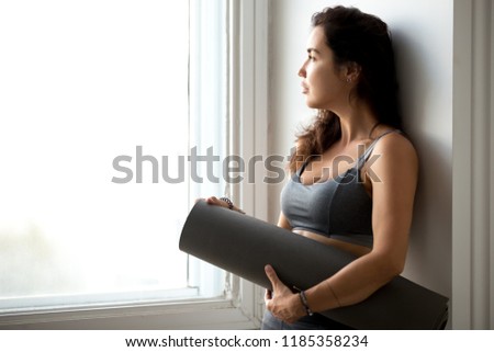 Stock photo: Photo Of Sporty Serious Woman Holding Yoga Mat And Looking Forward