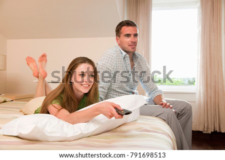 Foto stock: Young Happy Couple Watching Tv At Home With Open Arms And Daydre