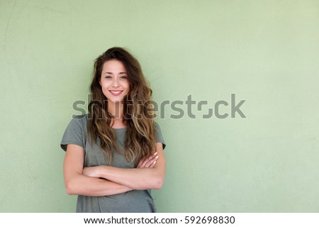 ストックフォト: Smiling Young Woman With Arms Folded Against A White Background