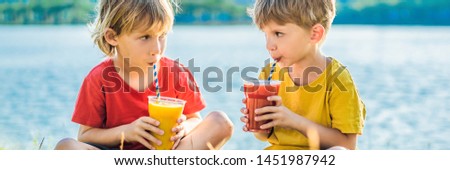 Foto d'archivio: Two Boys Drink Healthy Smoothies Against The Backdrop Of Palm Trees Mango And Watermelon Smoothies