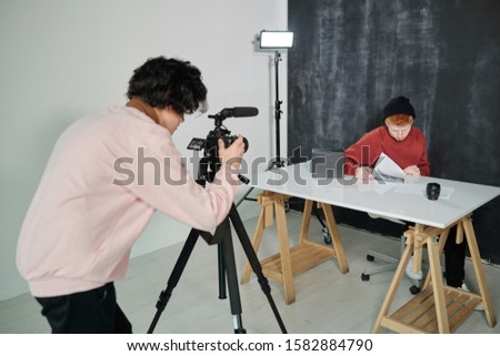 [[stock_photo]]: Guy In Casualwear Bending In Front Of Video Camera While Shooting Male Vlogge