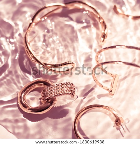 Foto d'archivio: Golden Bracelets Earrings Rings Jewelery On Pink Water Backgr