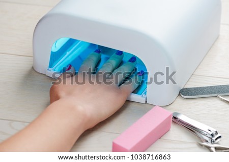 Foto d'archivio: Woman Hands Care Manicured Nails In Uv Lamp Rays Cure Gel Polish Small Nail Art And Manicure Busi