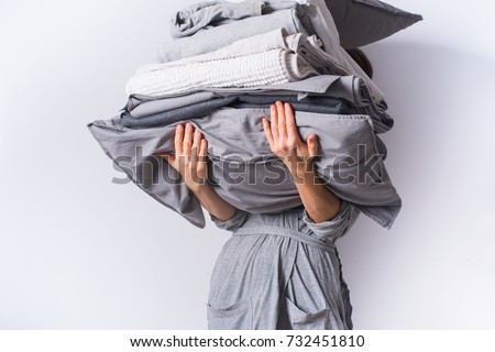 [[stock_photo]]: Woman Holding Stack Monochrome White And Gray Bed Linen Textiles