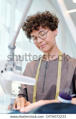Pretty Young Seamstress In Eyeglasses Working Over New Fashion Collection Foto stock © Pressmaster