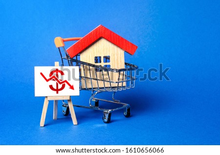 Foto stock: Wooden Houses In A Shopping Cart And An Easel With A Red Euro Arrow Down Chart Low Sales Value Cos