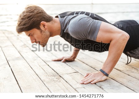 Foto stock: Concentrated Sports Man Outdoors On The Beach Make Sport Exercises