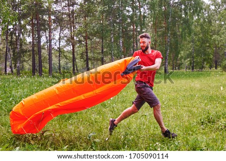 Stockfoto: Summer Lifestyle Portrait Of Man Inflates An Inflatable Orange Sofa On The Beach Of Tropical Island
