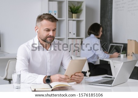 Zdjęcia stock: Serious Office Worker Looking At Touchpad Display While Watching Online Training