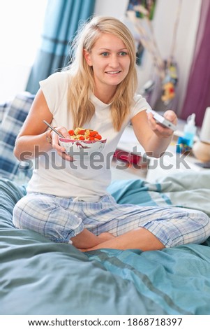 Stock fotó: A Vertical Shot Of A Woman In Bed With A Bowl Of Cereal As She Smiles And Looks At The Spoon Of Cer