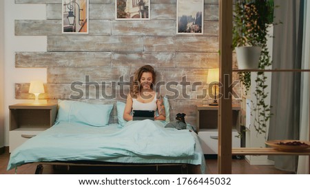 Foto stock: Young Woman Using Her Tablet Computer In Her Bed Late At Night