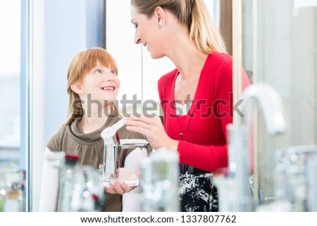 Foto stock: Happy Mother Looking With Her Daughter At Two Faucets In A Sanitary Ware Shop