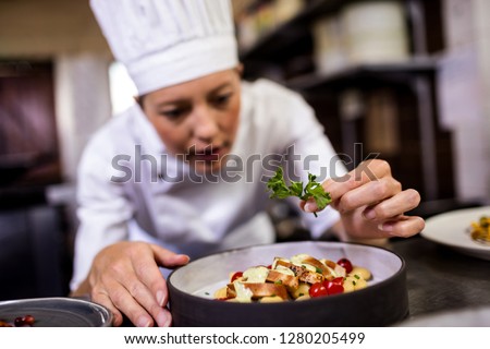 Stok fotoğraf: Female Chef Garnishing Delicious Desserts In A Plate At Hotel