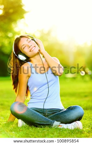 Zdjęcia stock: Student Outside Sitting On Green Grass And Listening Music Via H