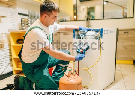 Stock foto: Serviceman In Overall Working On Fridge