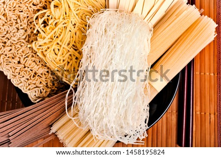 ストックフォト: Bundle Raw Asian Noodles In Plate With Chopsticks On Black Striped Mat Background With Copy Space T