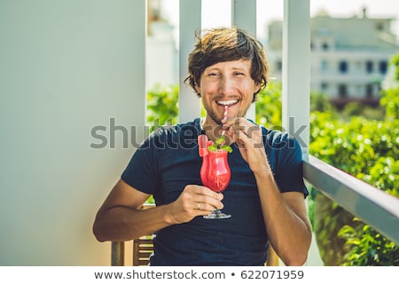 Foto stock: Man Is Holding Healthy Watermelon Smoothie With Mint And Striped Straws On A Wood Background