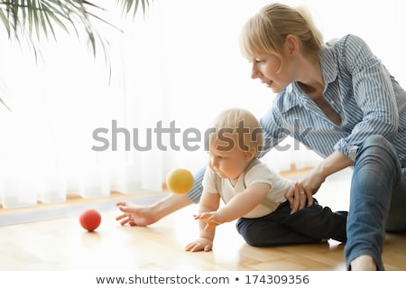 Stock fotó: Happy Mother And Her 1 Year Old Son Playing With Small Ball At Home
