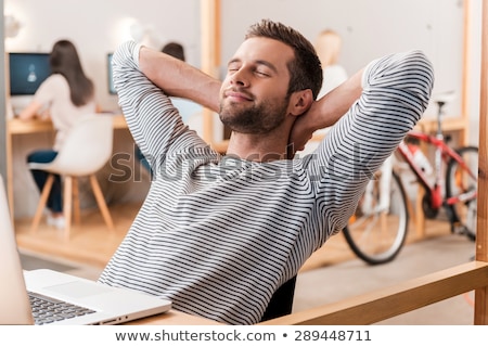 Stock fotó: Young Casual Man Sitting And Holding His Hands Behind Head