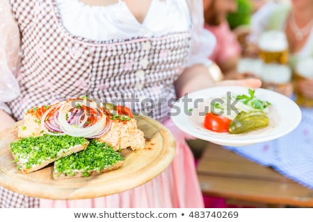 Foto stock: Waitress Serving Bavarian Food In Beer Garden
