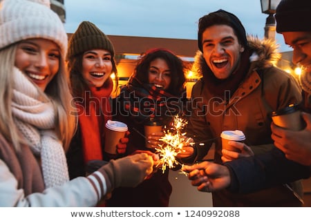 Imagine de stoc: Young Friends Talking With Each Other Drinking Coffee Outdoors Winter Concept Holding Bengal Lights