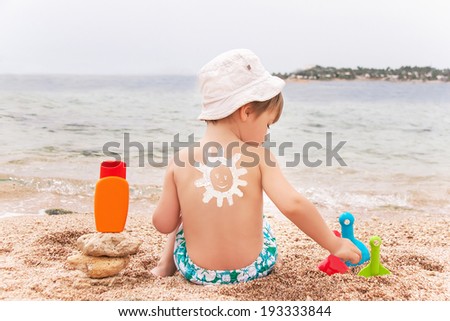 Stock fotó: The Sun Drawing Sunscreen Suntan Lotion On Baby Boy Back Caucasian Child Is Sitting With Plastic C