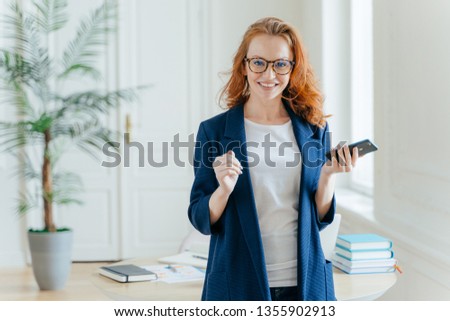 Stock photo: Smiling Prosperous Ginger Female Banker Makes Payment On Online Servie Waits For Important Call Ho