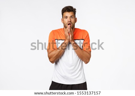 Stock photo: Shocked Anxious Young Handsome Male Athlete In Sports T Shirt Gasping Cover Mouth With Arms And S