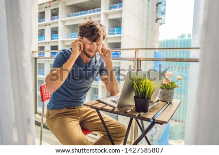 Foto stock: Young Man Trying To Work On The Balcony Annoyed By The Building Works Outside Noise Concept Air Po