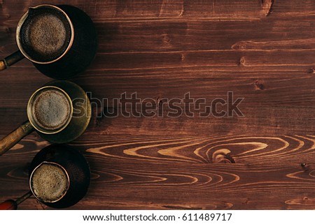 Foto stock: Hot Coffee In Shabby Turkish Pots Cezve With Tasty Crema With Copy Space On Brown Old Wooden Board B