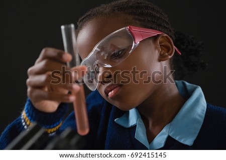 Stok fotoğraf: Attentive Schoolgirl Doing A Chemical Experiment Against Black Background