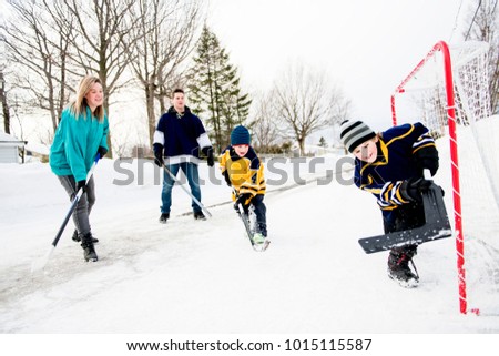 Stok fotoğraf: Happy Funny Kids Playing Hockey With Father And Mother On Street In The Winter Season