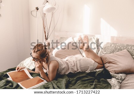 Foto d'archivio: Smiling Blonde Woman Sitting In Her Bed In Bright Bedroom Under Quilt