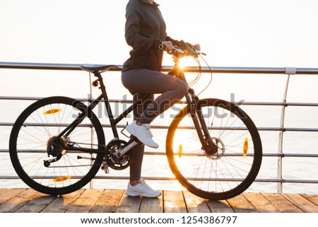 Stok fotoğraf: Photo Of Slim Woman Riding Bicycle On Boardwalk During Sunrise