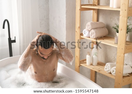 Stockfoto: Wet Young Muscular Man Washing His Hair While Having Bath With Foam