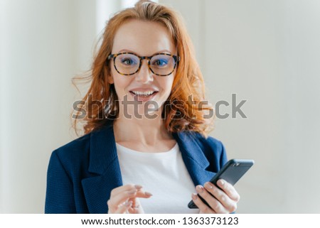 Stock photo: Headshot Of Female Banker With Pleasant Appearance And Red Hair Does Banking Online On Cell Phone