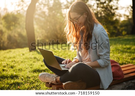 Stock foto: Young Pretty Woman With Laptop Sitting On The Bench In A Park