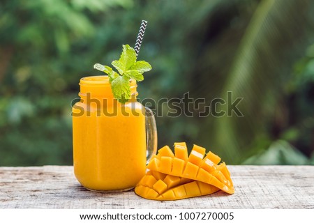 Foto stock: Mango Smoothie In A Glass Mason Jar And Mango On A Green Background Mango Shake Tropical Fruit Con