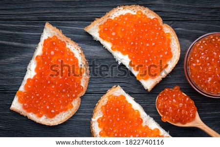 Stok fotoğraf: Salmon Red Caviar In Bowl And Sandwiches With On Wooden Cutting Board