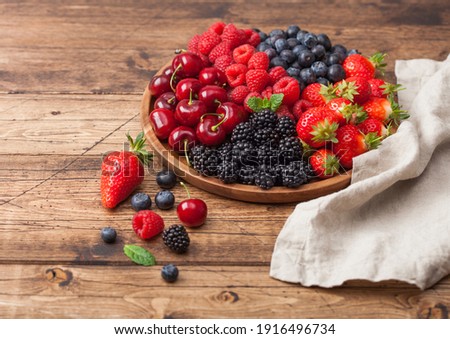 Stockfoto: Fresh Organic Summer Berries Mix In Round Wooden Tray On Black Kitchen Table Background Raspberries