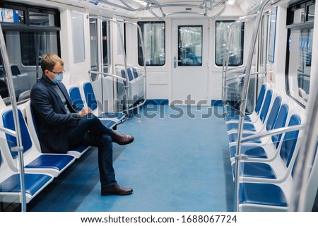 Stockfoto: Man Uses Medical Face Mask Sits Alone In Metro Carriage Commutes To Work By Public Transport Avoi