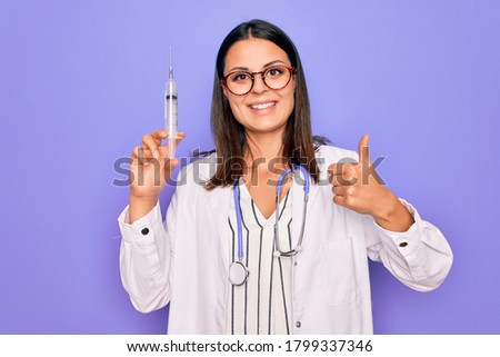 Stockfoto: Young Positive Brunette Doctor Woman With Syringe Isolated On White