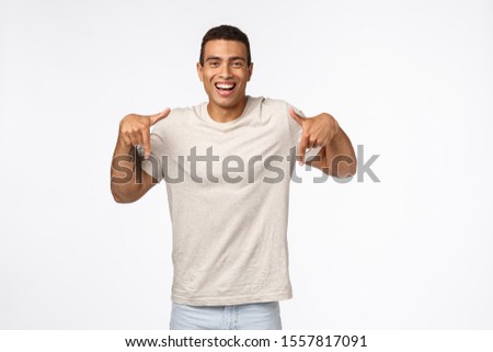 Stock photo: Muscline Good Looking Tanned Strong Man In Casual T Shirt Pointing Down Smiling Satisfied And Happ