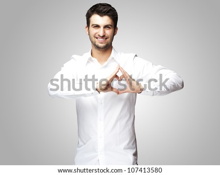 Сток-фото: Portrait Of Young Man Doing Heart Gesture Against A Gray Background