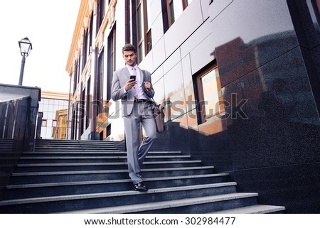 Stock photo: Businessman Walking On The Stairs And Using Smartphone Outdoors