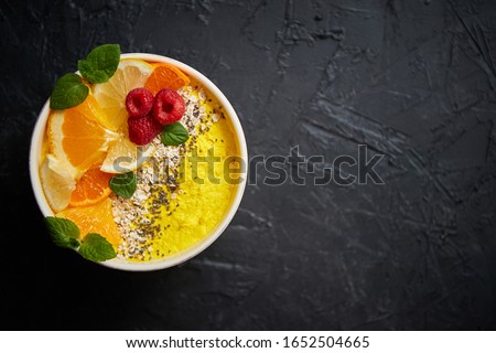 Foto d'archivio: Tasty Orange Fresh Smoothie Or Yogurt Served In Bowl With Raspberries Orange Slices Chia Seeds