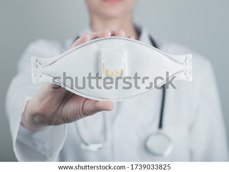 Stockfoto: Doctor Holding Respiratory Face Mask On Grey Hospital Wall Background Best Prevention From Coronavi